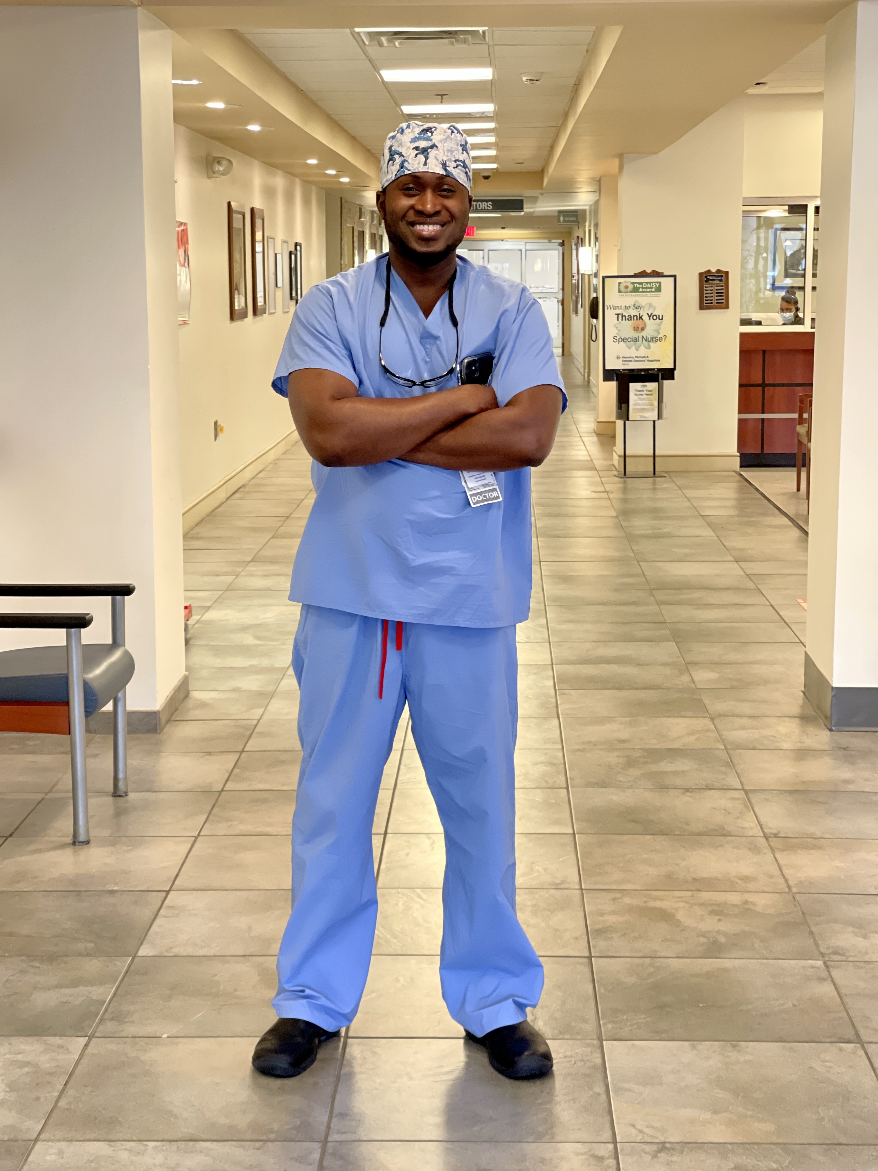 Dr. Kwadwo Owusu-Akyaw standing in hospital hallway in scrubs with arms crossed