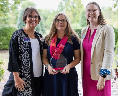 Donna Wilson standing with two coworkers, smiling and holding a glass award honoring her service at Henrico Doctors' Hospital.