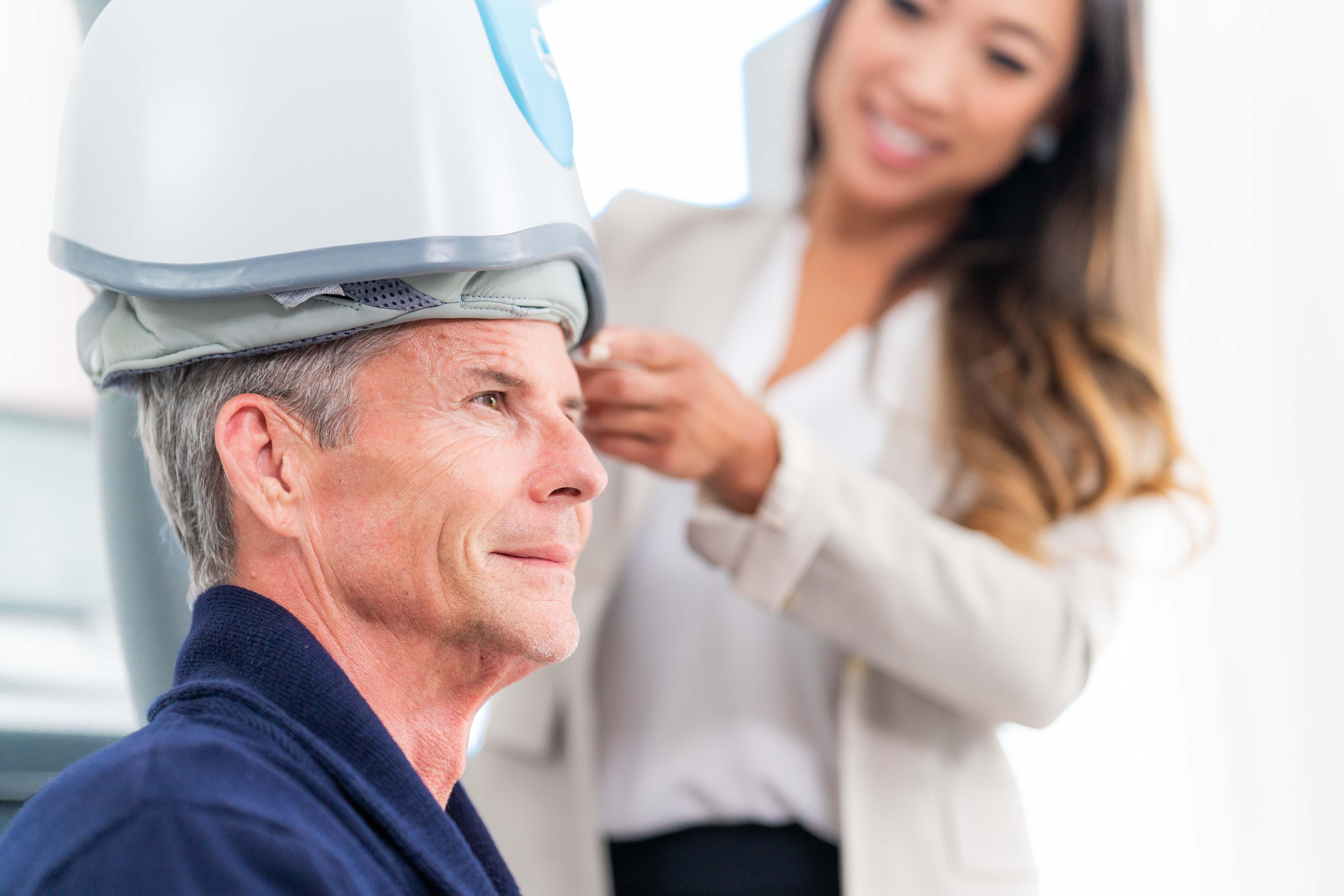 Elderly man receiving Transcranial Magnetic Stimulation (TMS) treatment for depression.