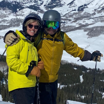 John Fulton and his wife posing for a picture while skiing in the mountains.