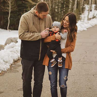 Breanne Armstrong with her husband Eric and baby Liam pose on a snow-lined street.
