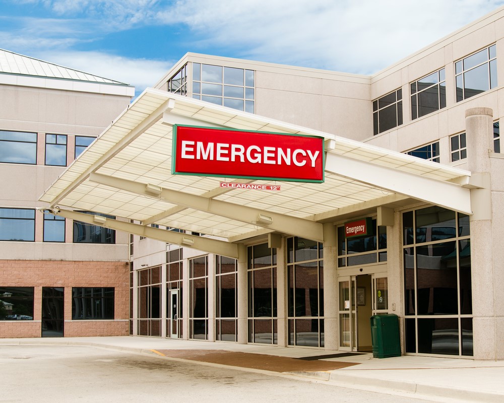 The entrance to a hospital with a sign that says, emergency above the door.