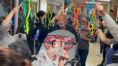 Baby Irina is wheeled down hallway with staff celebrating her recovery