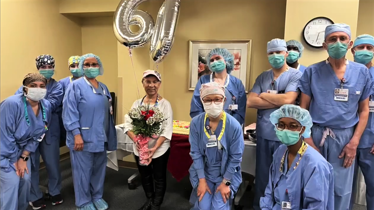 Rose holding a bouquet of flowers and a 60th anniversary balloon, surrounded by medical staff from Rose Medical Center.