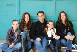 Jennifer Halvas sitting on the ground with her husband and three kids.