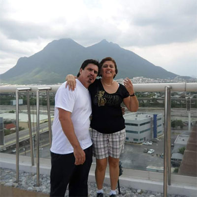 Arturo and a female friend stand before a scenic mountain vista.