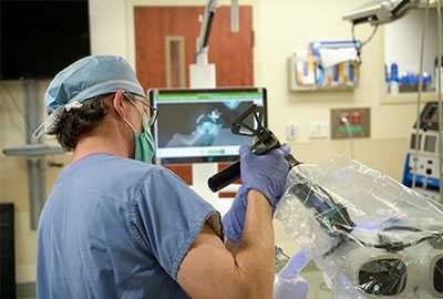 A doctor performs surgery in an operating room using robot-assisted technology.
