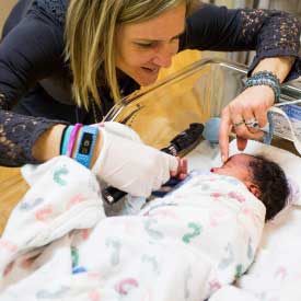Neonatal nurse caring for a swaddled newborn baby.