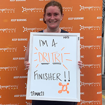 Mackenzie Mitchell holding a sign that says "I'm a dritri finisher!!".