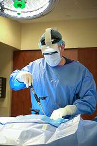 A doctor performs spinal surgery in an operating room with the assistance of augmented reality.
