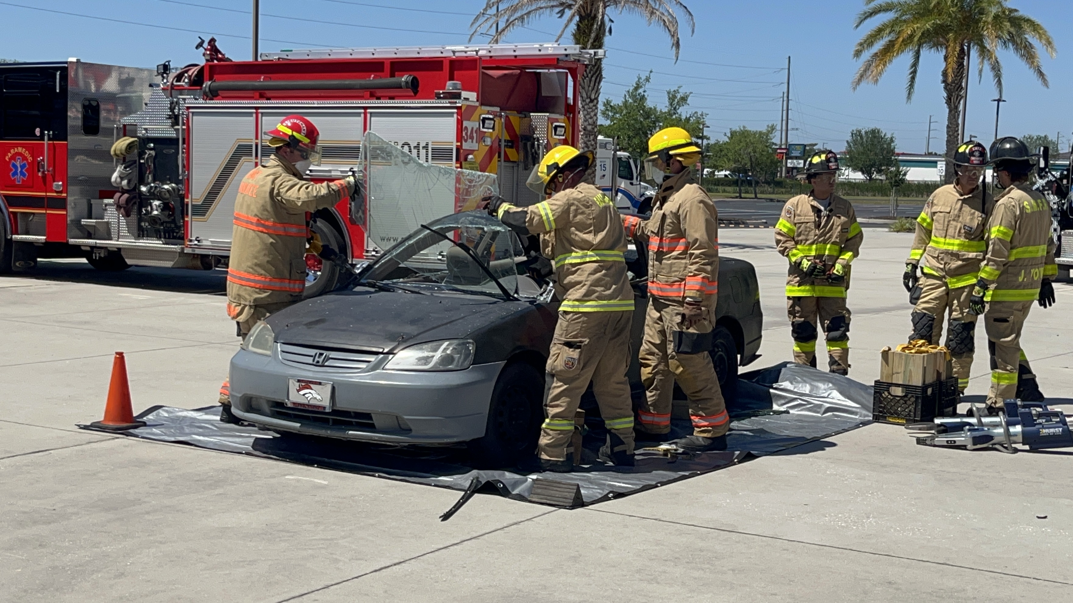 Firefighters remove windshield from car as part of entrapped victim demonstration.