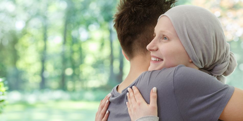 A woman wearing a head covering smiles while hugging a friend.