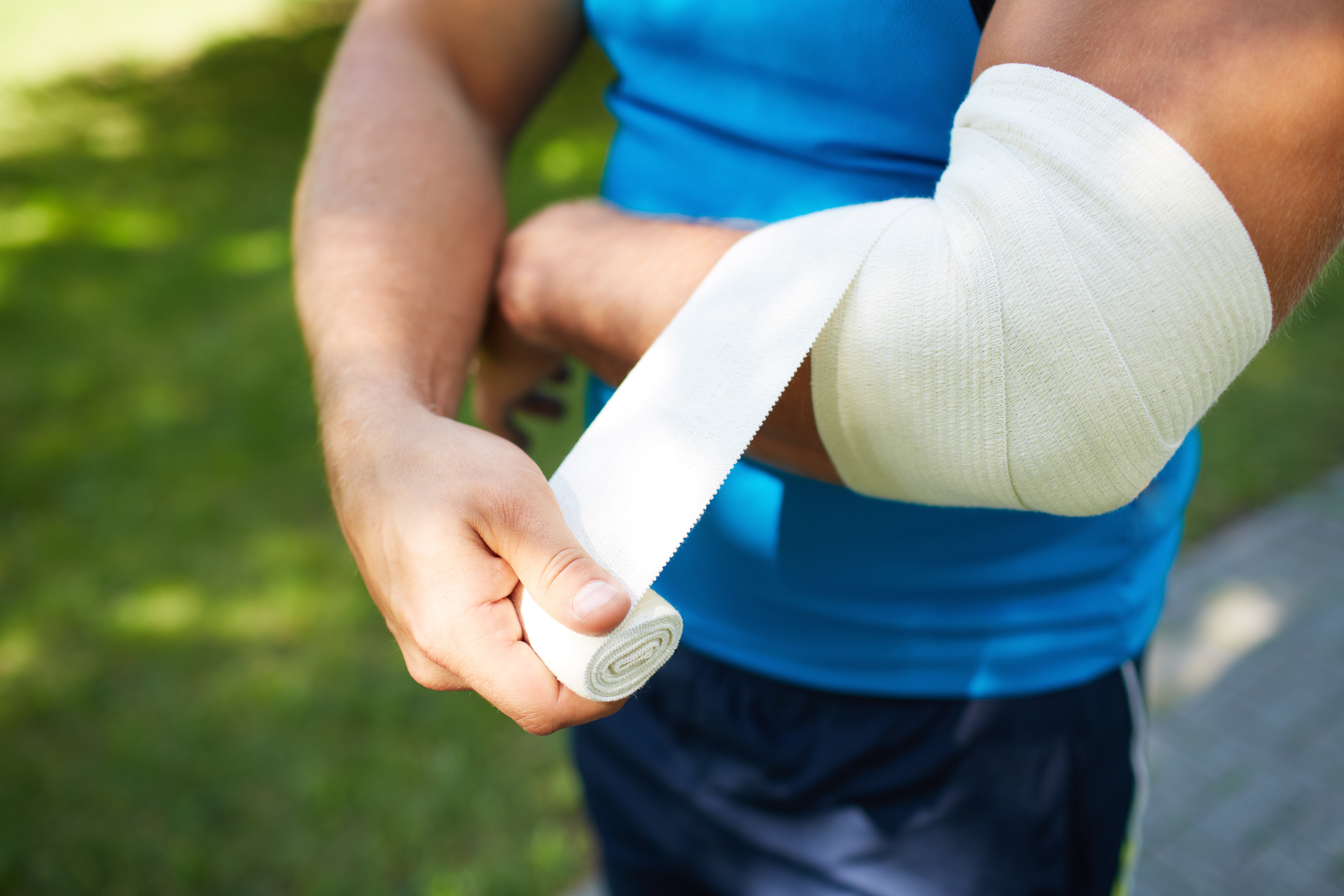 A person wrapping their elbow with a bandage.