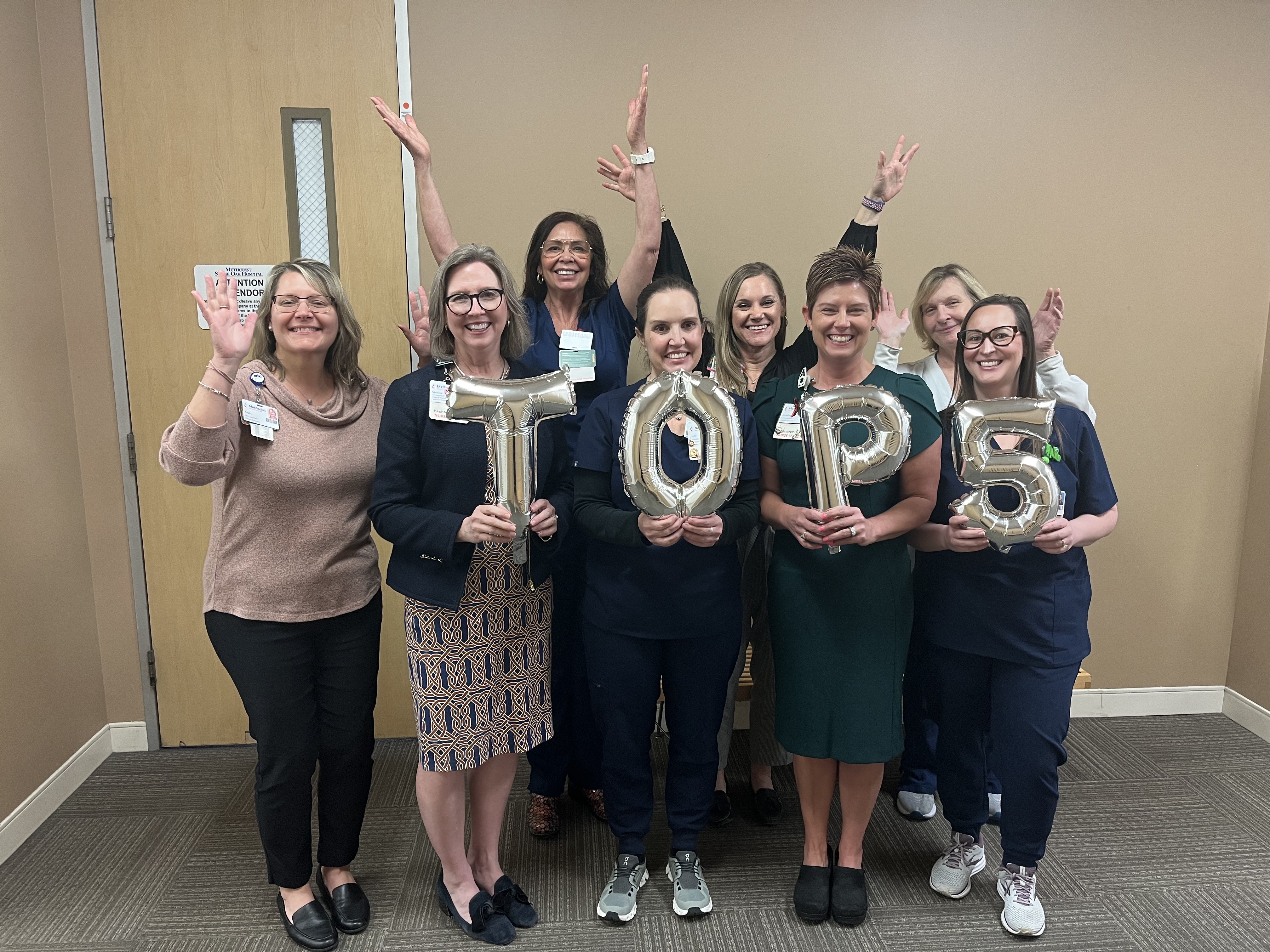 A group of nurses holding balloons that spell out 'Top 5'.