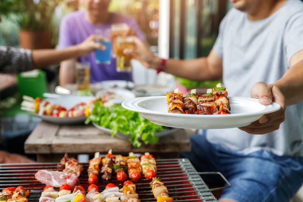 A man grills skewers with vegetables and meat.