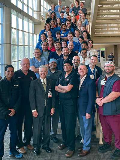 The HCA Houston Healthcare Clear Lake Cardiovascular Thoracic team and hospital executives pose on a hospital staircase.