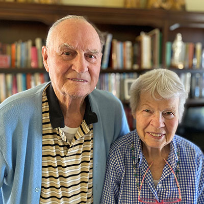 Ralph and Anne Mitchell pose in front of a bookcase