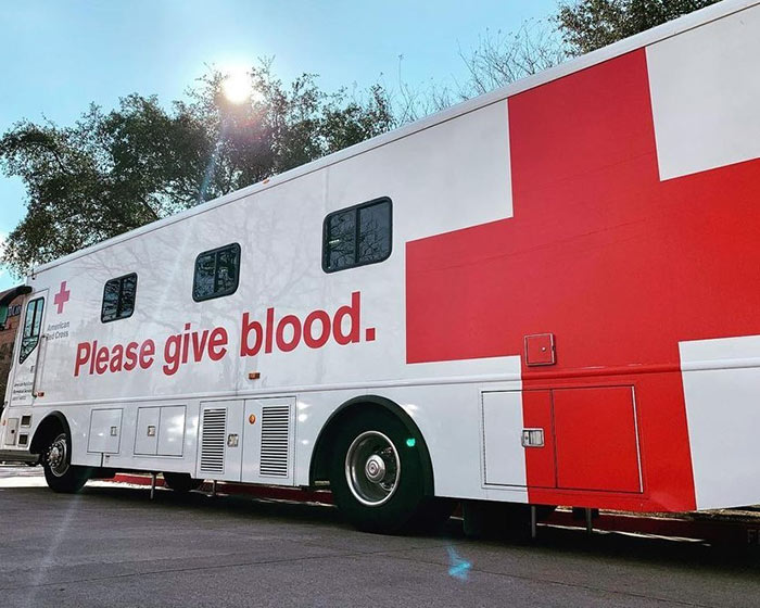 An American Red Cross mobile blood donation bus with the words, "Please give blood" on the side of the bus.