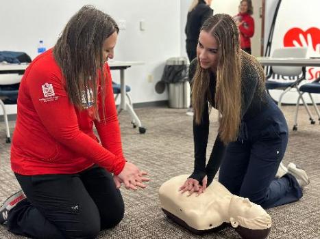 One women demonstrates the proper technique while another woman performs CPR chest compressions on a mannequin during a recent training.