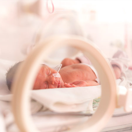 A premature baby in a neonatal intensive care unit incubator.