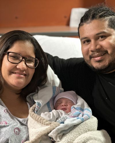 Crhystell Guzman and Axel Peralto smile while holding their new baby, Angel, the first baby born in 2024 at Research Medical Center.