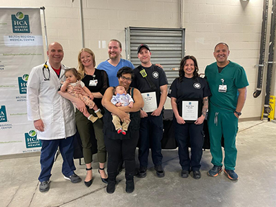 Victoria Osorio smiles while standing with the medical care team that helped her during her recently emergency delivery of her baby.