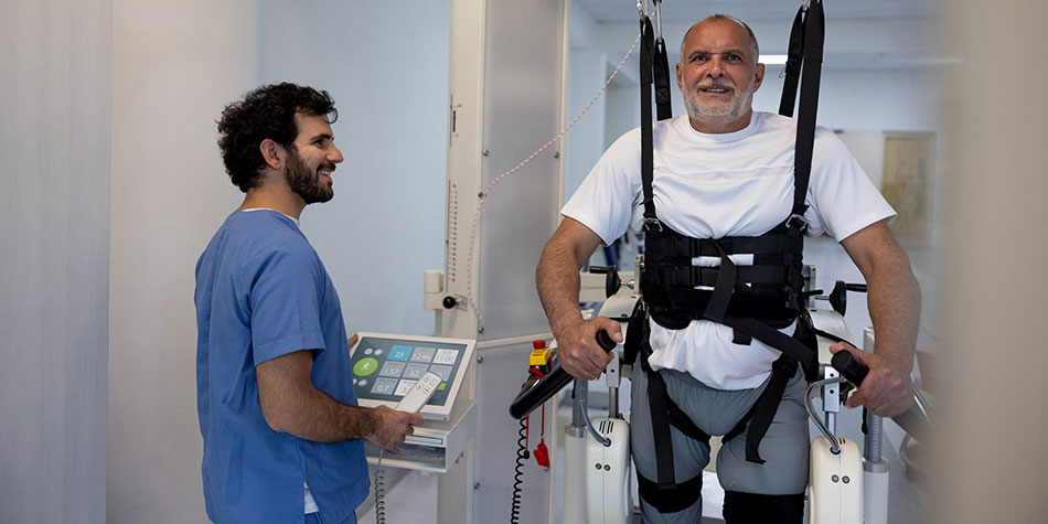 A rehabilitation staff member monitors a patient in a harness system.
