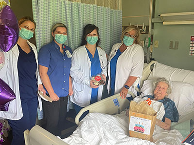 Community Caregivers stand next to the bedside of Ellen 'Dorothy' Mortenson.