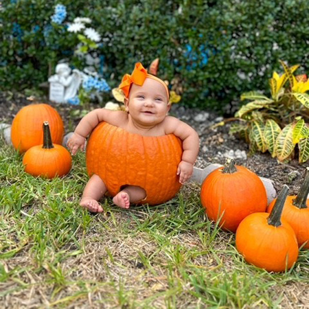 Mikaela Mayton sitting inside of a carved pumpkin.