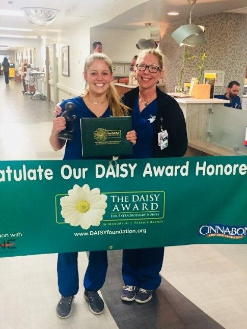 Jennifer Harlan smiles and poses with a Daisy Award winner.