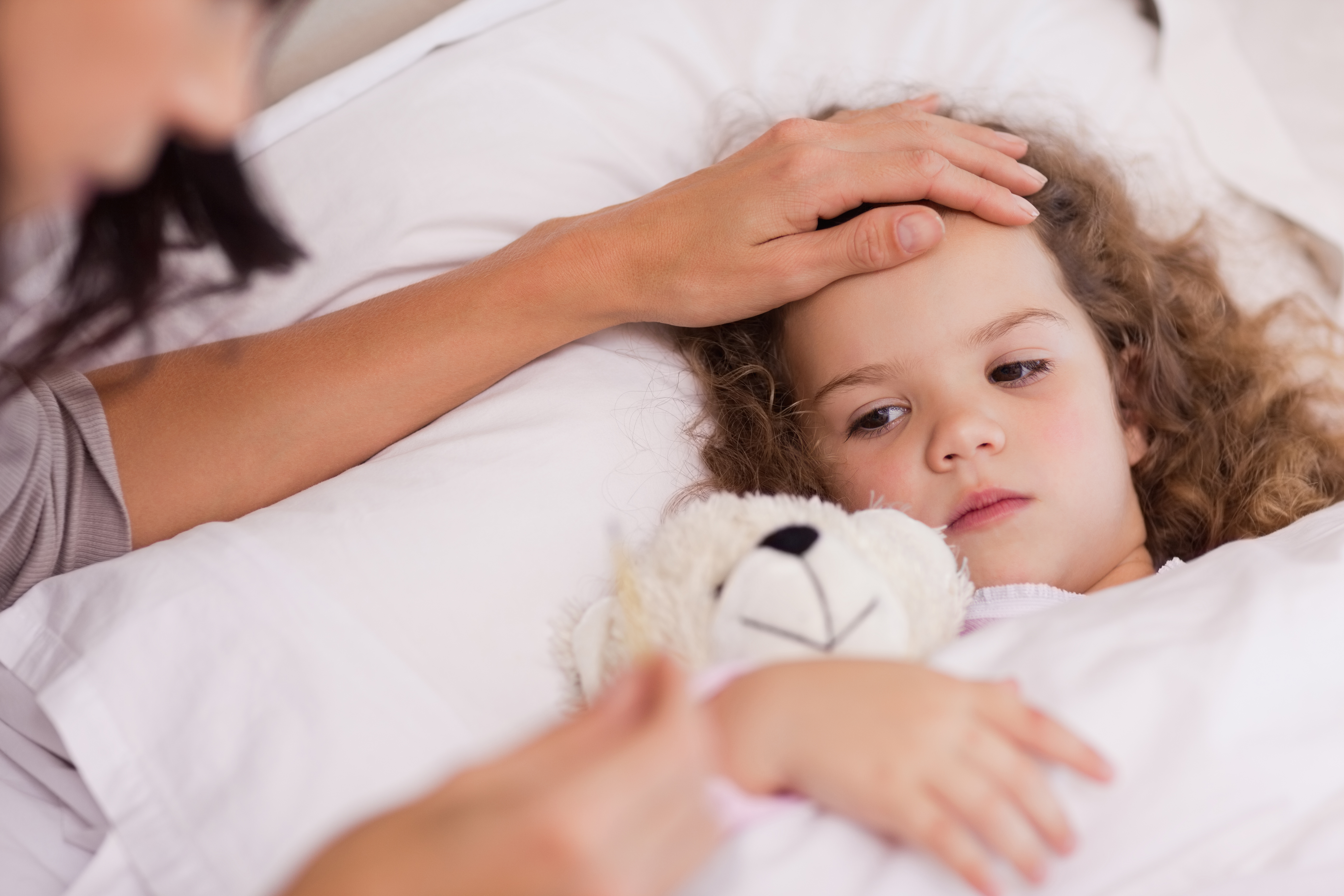 Mother feeling a sick child's forehead