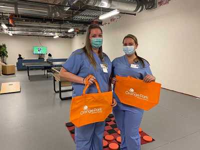 Two nurses hold Orange Park Medical Center tote bags in the fun room.
