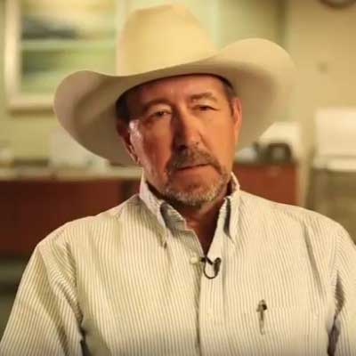 Bob Ellis, wearing a grey and white stripe shirt and a cowboy hat.