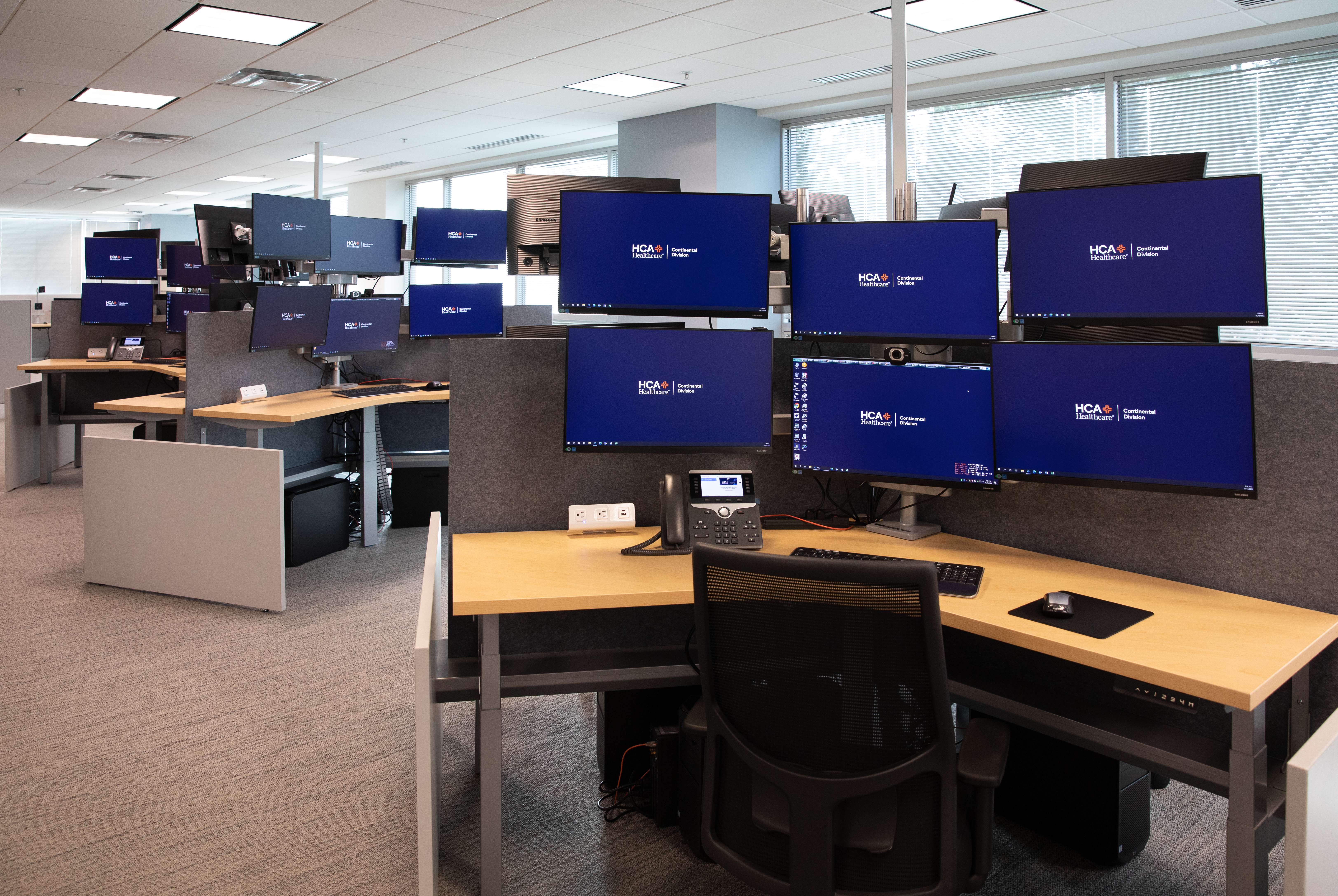 An office setting displaying computer desks with 6 monitors at each desk.