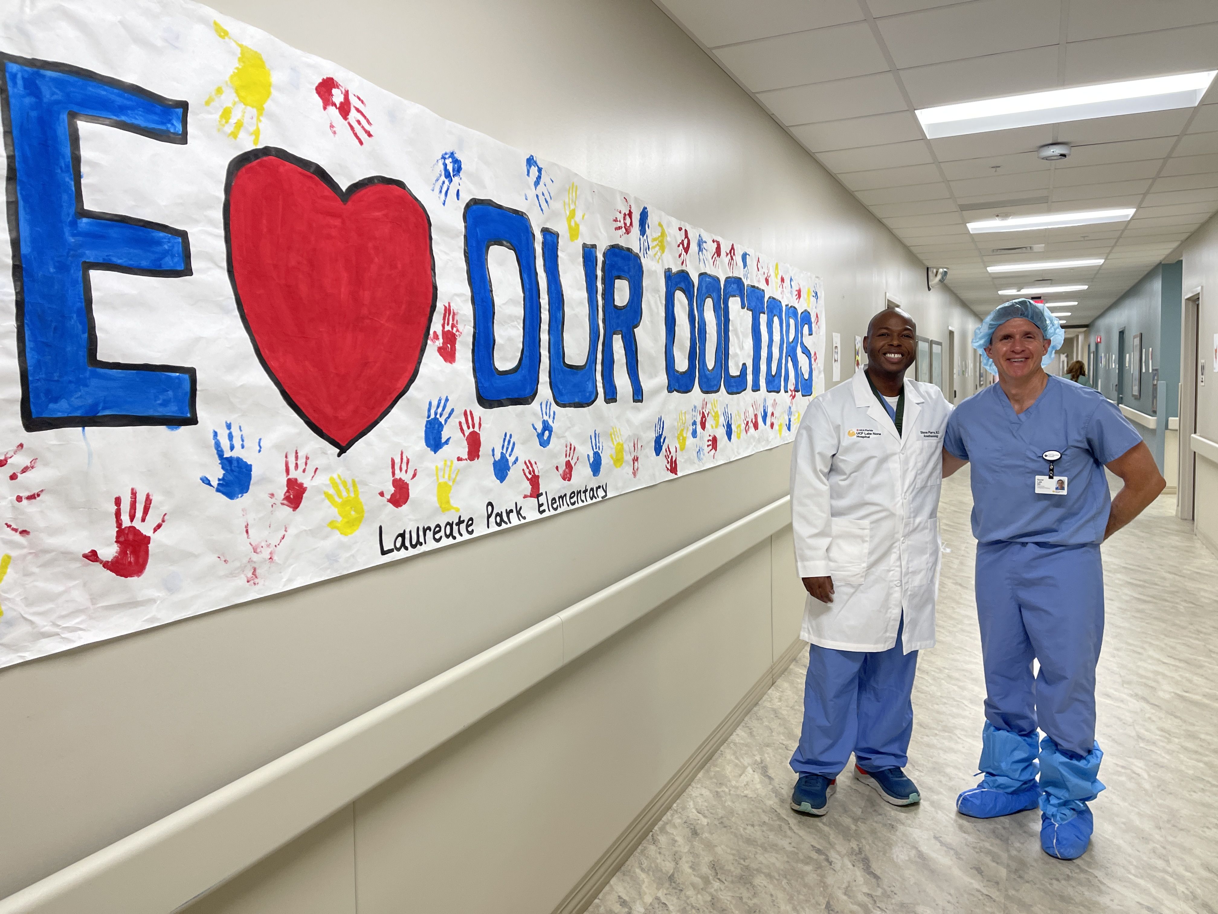Doctors standing by artwork from local students displayed in hospital main corridor.