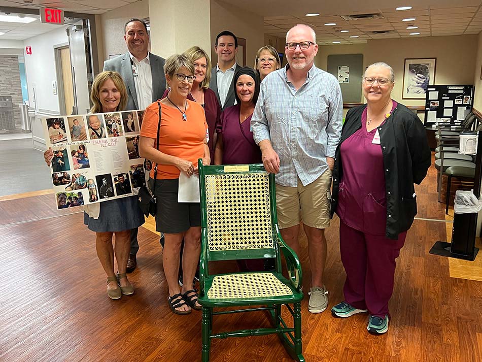 A family standing with a nurse behind an empty green chair.