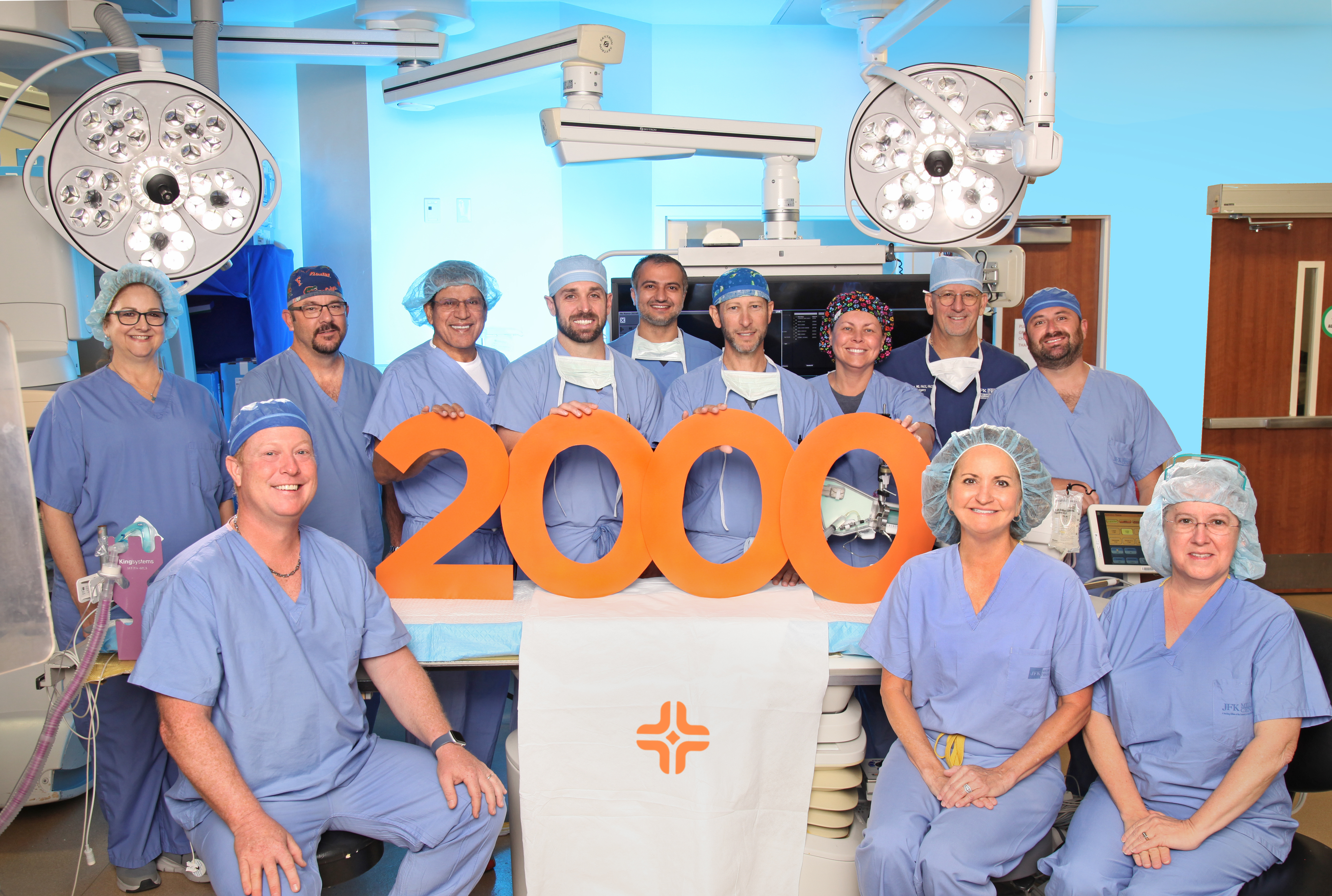 JFK Hospital's TAVR team celebrates 2,000th TAVR procedure, holding "2000" sign in surgery room
