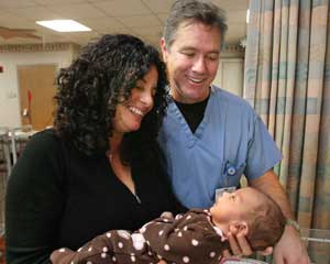 Joe Toney, MD, Medical Director of the NICU at Sky Ridge, looks on as Monica McFarland proudly admires her baby girl, Lilly.