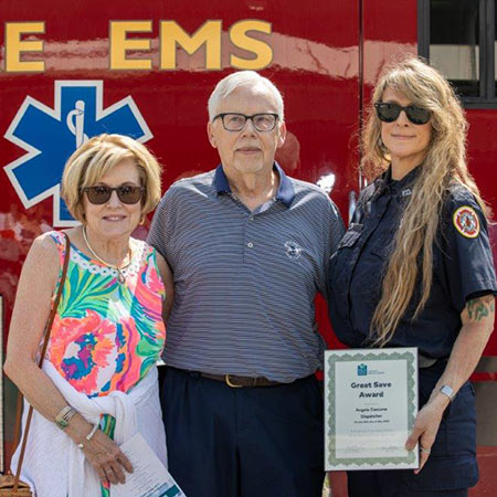 Steve Redmund smiles while standing with his wife and one of the EMS professionals who responded to his 911 call for help.
