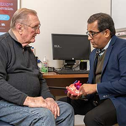Francis Wichman talks with a doctor who is holding a model of a human heart.